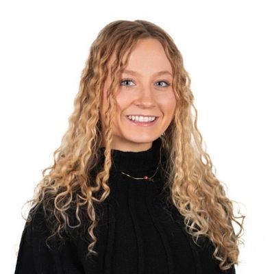 Smiling woman with long curly blonde hair wearing a black sweater.