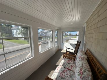 Cozy porch with floral couch and rocking chair.