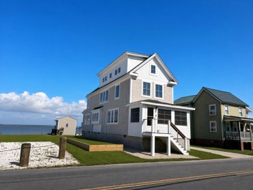 Three houses on a coastal street with a blue sky.