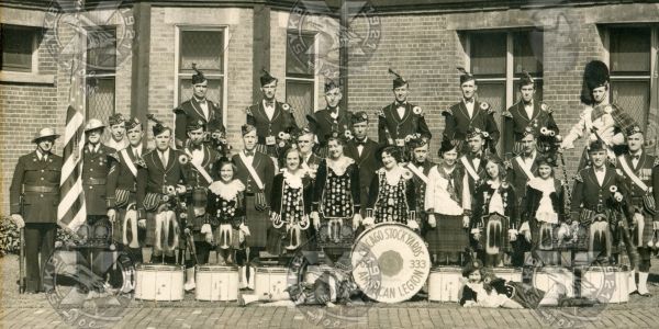 Vintage group photo of a marching band in traditional attire with drums and kilts.