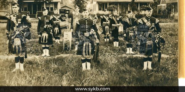 A group of men in traditional Scottish military uniforms standing outdoors.