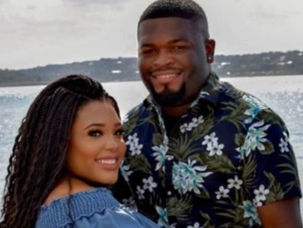 Smiling couple posing by the water with a scenic background.