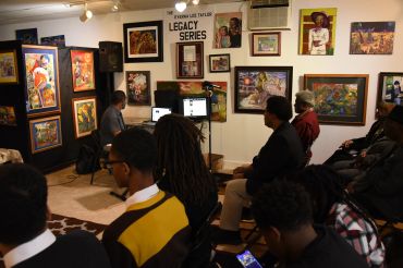 People attending an art exhibit titled Legacy Series.
