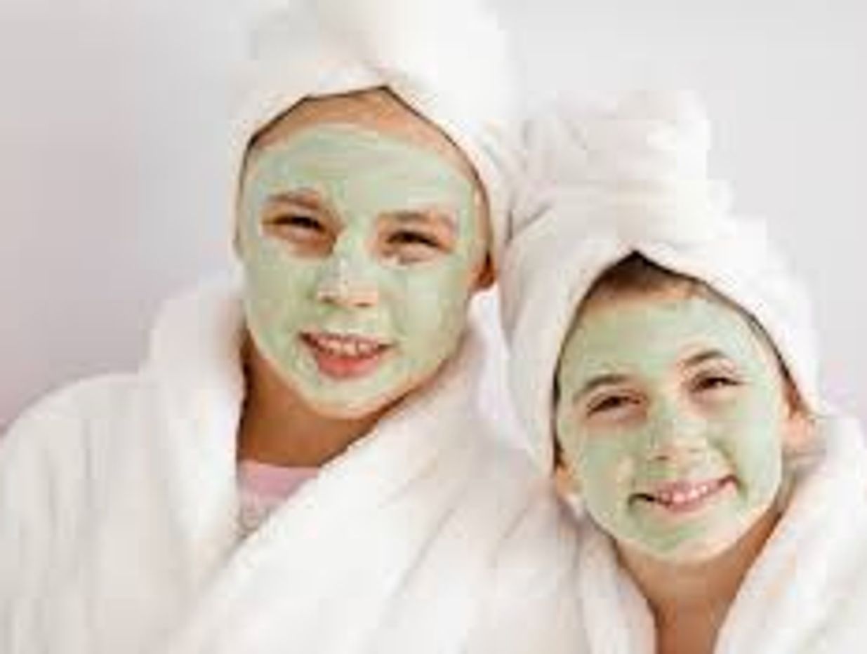 Two people relaxing with green facial masks and white towels on their heads.