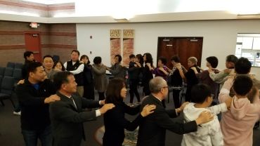 People in a line giving shoulder massages to each other indoors.