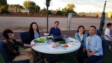 Group of friends enjoying an outdoor meal around a table with food.