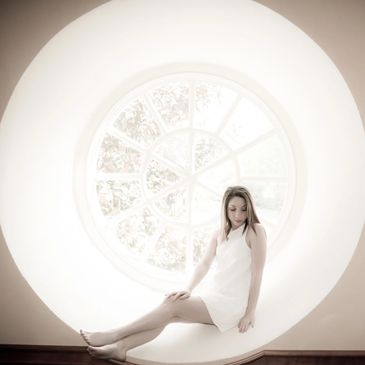 Photograph by Kelly Hazel. Portrait of a young woman in a window.