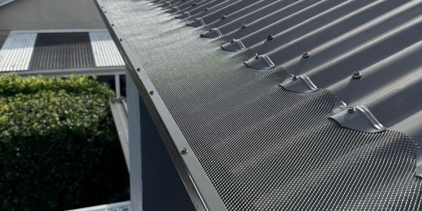 Close-up of a gray metal roof with a mesh guard on the edge.