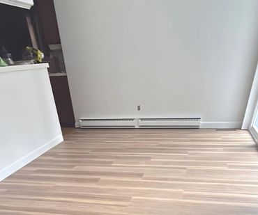 Empty room with light wood flooring and white walls.