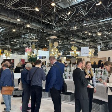 People mingling and tasting drinks at a bustling indoor event.