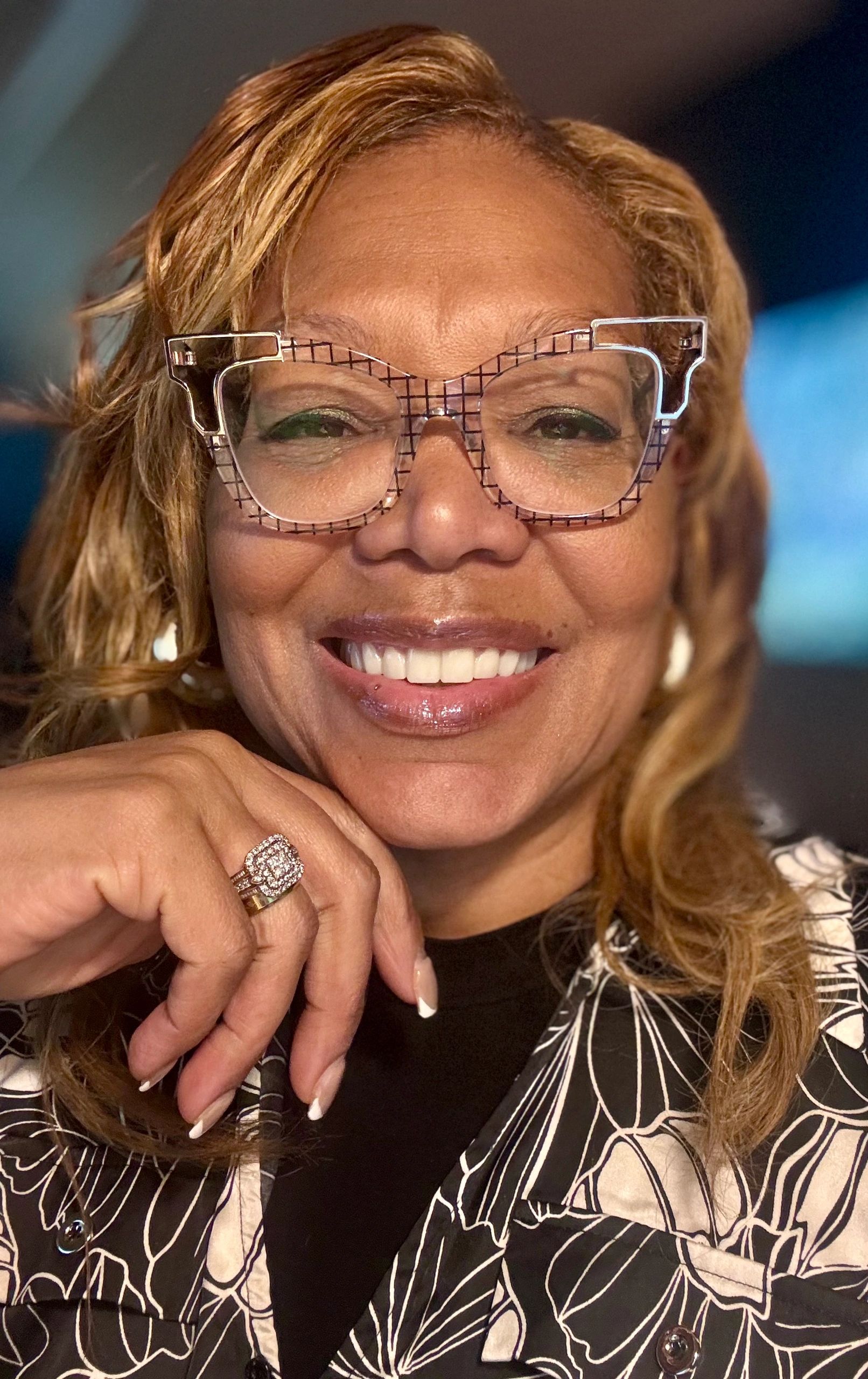 Smiling woman with checkered glasses and a ring.