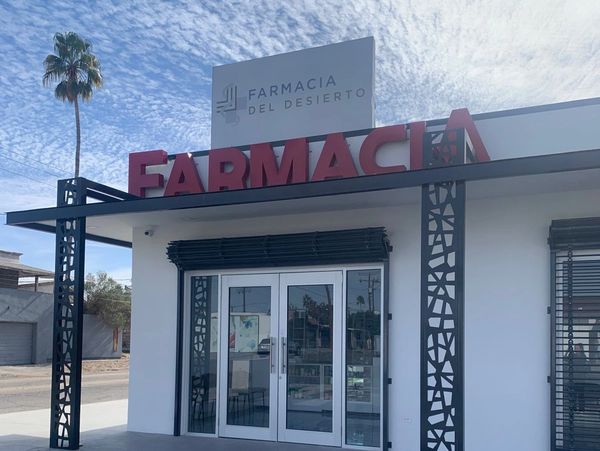 Modern pharmacy entrance with bold red signage and decorative black metal columns.