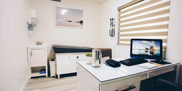 A clean, modern medical examination room with a computer and examination table.