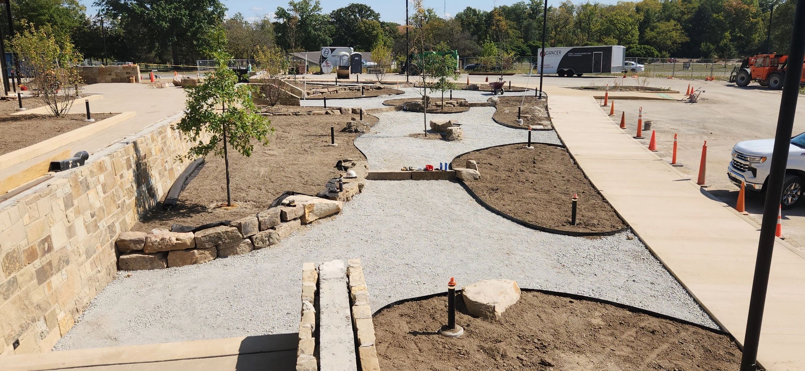 A landscaped garden area under construction with pathways and small trees.
