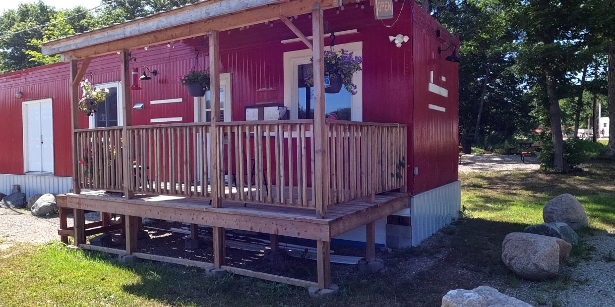 Small red building with a wooden porch and hanging plants.