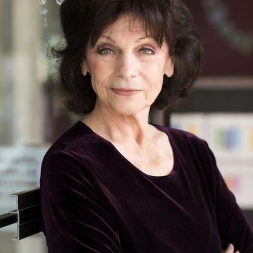 Portrait of a confident older woman in a dark velvet top.