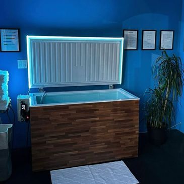 Modern cryotherapy chamber with wooden exterior and blue ambient lighting.