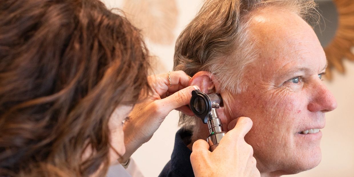 Dr Heather Smith, audiologist, looking into patient's ear.