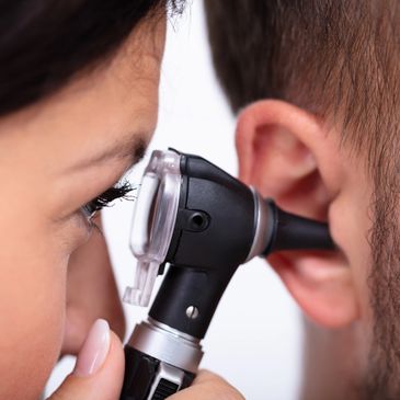 Dr Smith is looking into a patients ear with an otoscope.