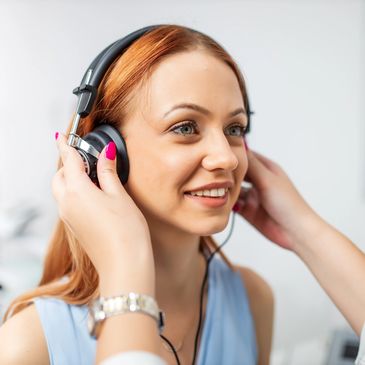 A young woman is wearing headphones for a hearing test or evaluation.