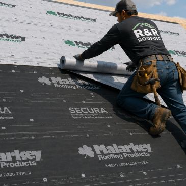 Worker installing roofing materials with R&amp;R Roofing shirt.