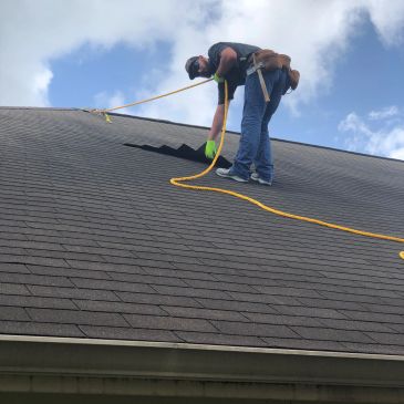 Worker repairing roof with safety rope.