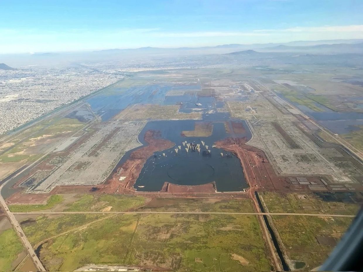 Aerial view of a large construction site with water bodies and surrounding landscape.