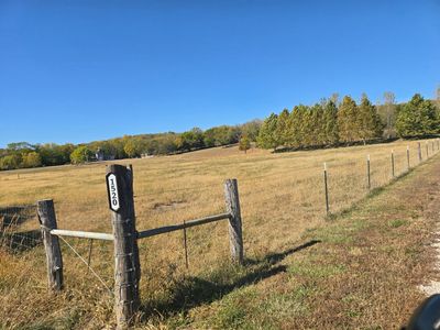 Rural fence with house number 1520 in a sunny countryside field.