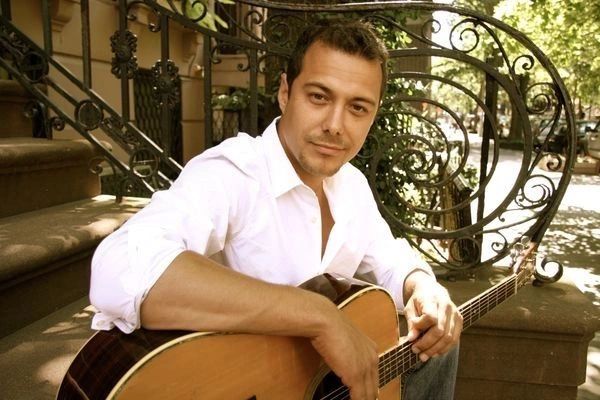 Derek Samuel Reese with his guitar on a stoop