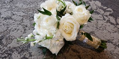 All white bridal bouquet with handle wrapped in gold ribbon laying on carpeted floor

