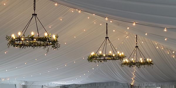 ceiling of tent, round light fixtures with greenery around the bottom edge 