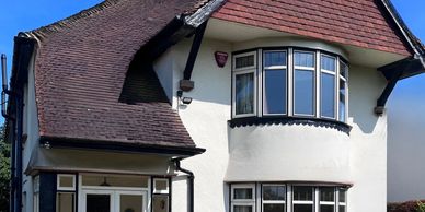 White two-story house with bay windows and a red tiled roof.