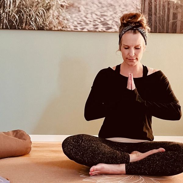 Yin-Yoga Lehrerin Jase in Schneidersitz und Namaste Haltung