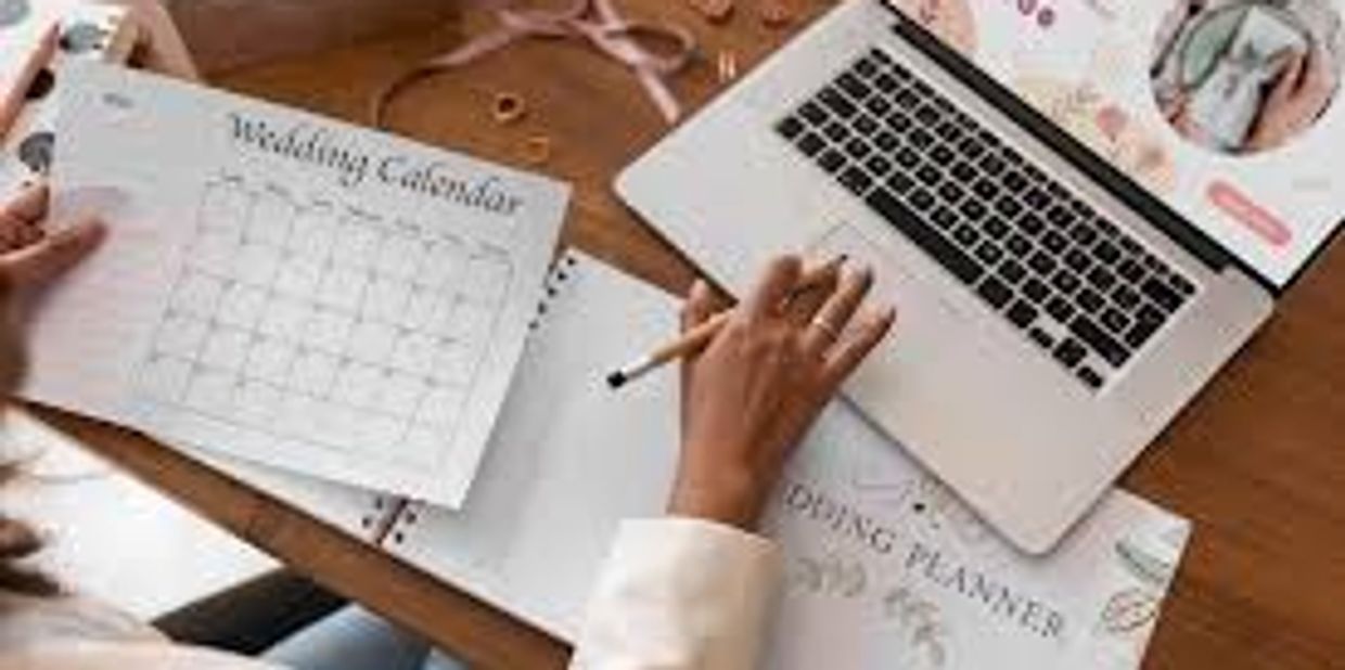 Person planning a wedding using a laptop and calendar.