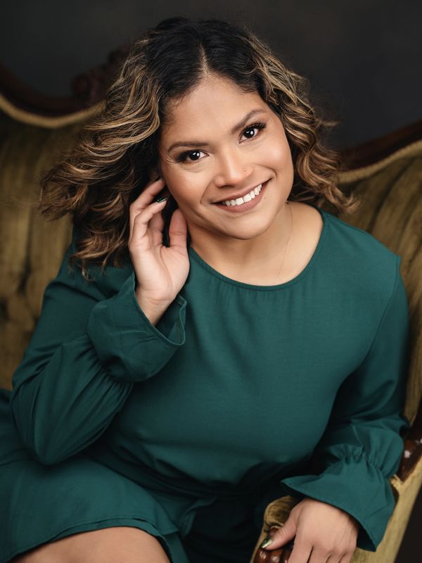 Smiling woman with curly hair in a green dress.
