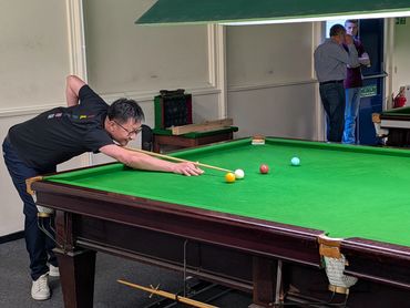 Man aiming for a shot on a snooker table.