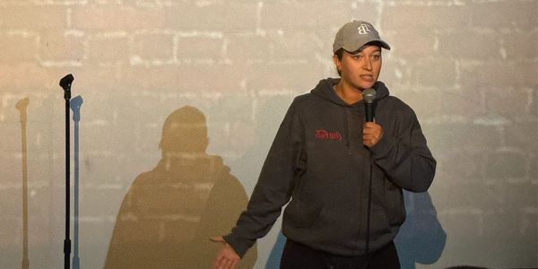 Comedian performing stand-up with microphone on stage.