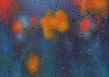 Raindrops on a window with blurred colorful lights.