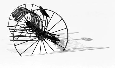 Antique hay rake casting shadow on snow.