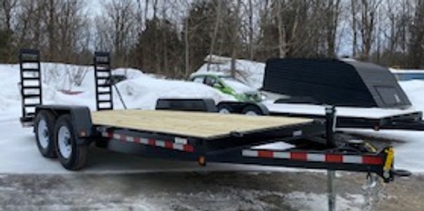 Flatbed trailer with wooden deck parked on snowy ground.