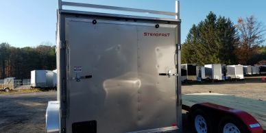 Rear view of a Steroplast enclosed trailer in a parking area.