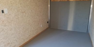 Empty room with OSB walls and a gray floor.