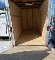Empty wooden trailer interior with open back door.