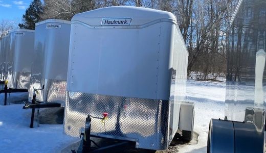 Row of Haulmark trailers parked on snowy ground under a clear sky.