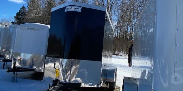 Haulmark trailers parked in a snowy lot with clear blue sky.