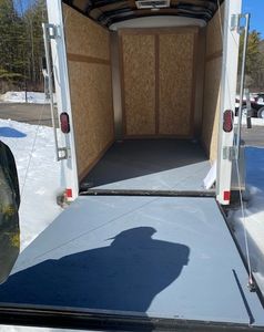 Empty trailer with open ramp door in a snowy outdoor setting.