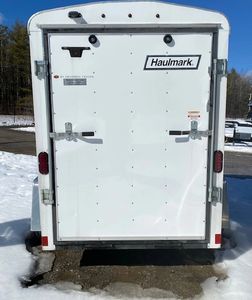 Rear view of a white Haulmark cargo trailer parked on snow.