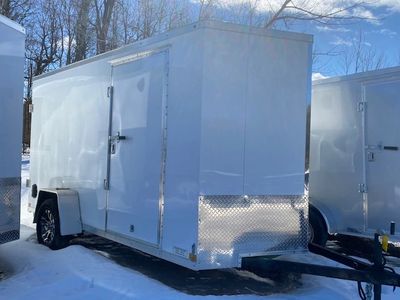 White enclosed cargo trailer parked on snow-covered ground under clear sky.