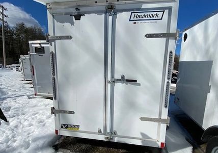 Rear view of a white Haulmark trailer in snowy weather.
