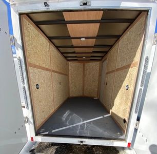 Empty cargo trailer with wooden paneling and metal frame.